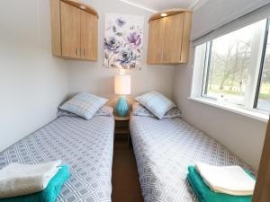 two twin beds in a small room with a window at The Four Oaks Chalet in Fassfern