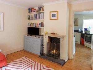 a living room with a fireplace and a kitchen at Woodhill Cottage in Holmbury Saint Mary
