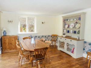 een eetkamer met een houten tafel en stoelen bij Woodhill Cottage in Holmbury Saint Mary