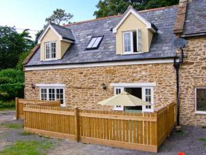 a brick house with a wooden fence and an umbrella at The Cygnet in Haselbury Plucknett