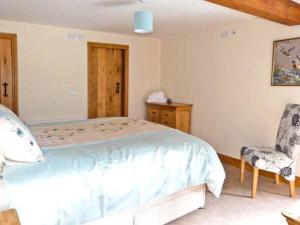 a bedroom with a large bed and a chair at Riddings Barn in Low Borrowbridge
