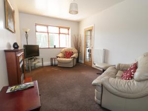 a living room with a couch and a tv at Hunters Moon Annexe in Fulford