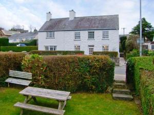 a wooden bench sitting in front of a white house at Glan Y Don in Abersoch