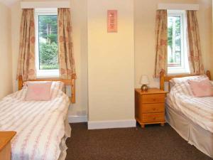 a bedroom with two beds and a dresser and two windows at Glan Y Don in Abersoch