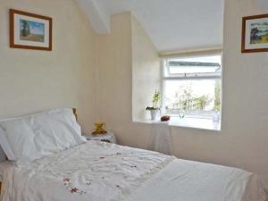 a bedroom with a white bed and a window at Coles Cottage in Holsworthy