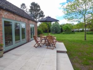 a patio with a table and chairs and an umbrella at Berringtons Barn in Lockleywood