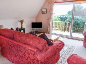 a living room with a red couch and a large window at Suil Na Mara in Aultbea