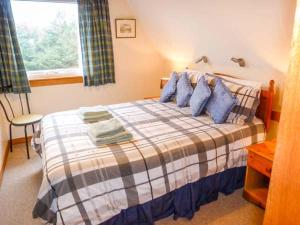 a bedroom with a bed with blue pillows and a window at Suil Na Mara in Aultbea