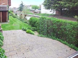 een tuin met een bakstenen pad naast een heg bij 9 Bancroft Place in Stratford-upon-Avon +1 foto