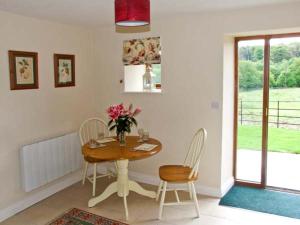 a dining room table with chairs and a vase of flowers at Hollins Wood Bothy in Wortley