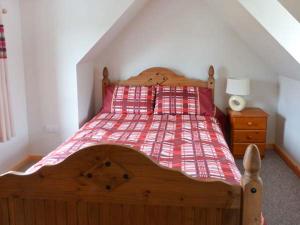 um quarto com uma cama de madeira e um cobertor vermelho em The Croft House em Muir of Ord