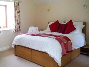 a bedroom with a large bed with white and red pillows at Hollins Wood Bothy in Wortley