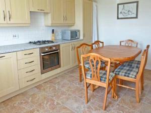 a kitchen with a wooden table and chairs and a stove at Kennels Cottage in Saint Boswells