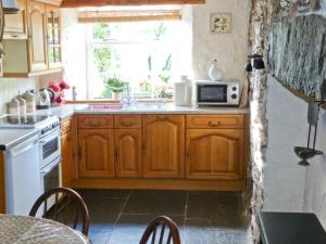 a kitchen with wooden cabinets and a sink and a microwave at High Kiln Bank Cottage in Ulpha +18 photos