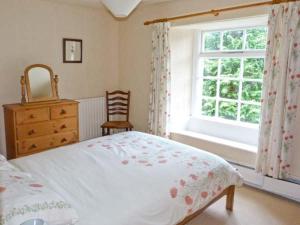 a bedroom with a bed and a dresser and a window at High Kiln Bank Cottage in Ulpha