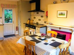 a kitchen with a table and chairs and a kitchen with a fireplace at Tan Y Rhos Isa in Llansantffraid Glyn Ceiriog