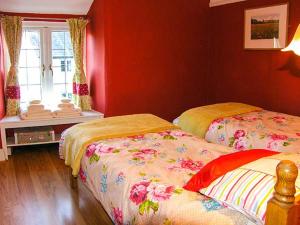 two beds in a room with red walls at Tan Y Rhos Isa in Llansantffraid Glyn Ceiriog