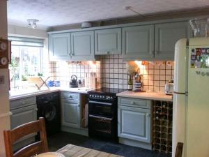 a kitchen with white cabinets and black appliances at Ted's Place in Aylsham
