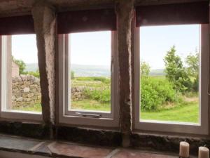 three windows in a room with a view of a field at Knowle Lodge in Mytholmroyd