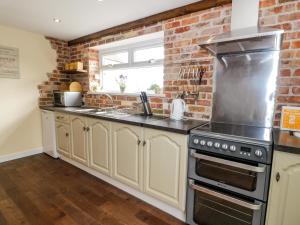 a kitchen with white cabinets and a brick wall at Ffynnonlwyd Cottage in Llangynin