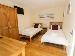 a room with two beds and a table in it at Ffynnonlwyd Cottage in Llangynin