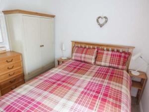 a bedroom with a bed with a plaid comforter and a dresser at Old Church Coach House in Church Leigh