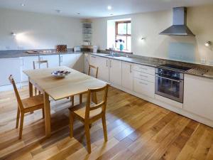 a kitchen with a wooden table and a wooden floor at Parsley Cottage in Conder Green