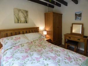 um quarto com uma cama e uma cómoda com um espelho em Cockley Beck Cottage em Coniston