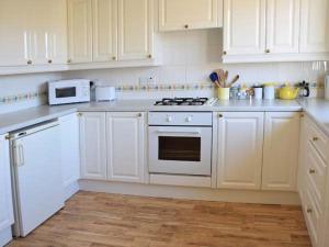 a kitchen with white cabinets and a white stove top oven at Amber's Cottage in Staffin