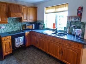 a kitchen with wooden cabinets and a sink and a window at Off Puddle Hill in Stowe