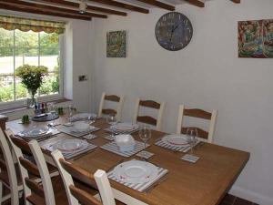 a dining room table with chairs and a clock on the wall at George Cottage in Clun