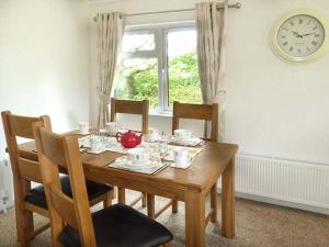 une table à manger avec des chaises et une horloge murale dans l'établissement Chaffinch Lodge, à Highampton