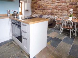 a kitchen with a stove and a table in a room at Herdwick's Barn in Wootton