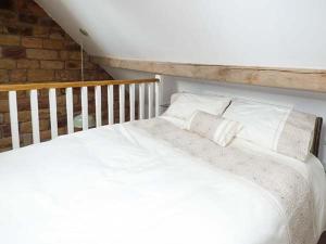 a bed with white sheets and pillows in a room at Herdwick's Barn in Wootton