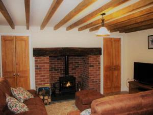 a living room with a brick fireplace and a couch at Maerdy Cottage in Bettws Gwerfil Goch