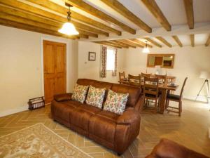 a living room with a brown leather couch and a dining room at Maerdy Cottage in Bettws Gwerfil Goch