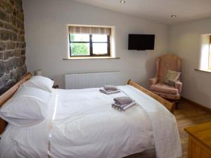 a bedroom with a large white bed and a chair at Upper Greenhills Farm in Foxt
