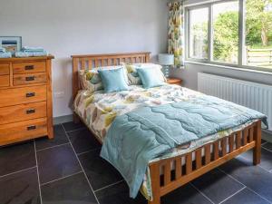 a bedroom with a wooden bed with a dresser and a window at The Lodge, Lower Trefedw in Pandy