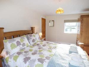 a bedroom with a bed with a comforter on it at Maerdy Cottage in Bettws Gwerfil Goch