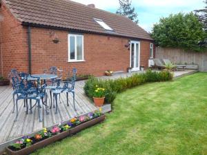 a wooden deck with a table and chairs in a yard at The Barn Ivy Cottage in Dunnington