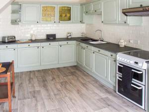 a kitchen with white cabinets and a wooden floor at Ganarew Cottage in Whitchurch