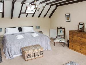 Ganarew Cottage في وايتشرتْش: غرفة نوم بسرير وكرسي وخزانة