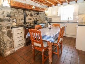 a kitchen with a table and chairs and a sink at Bod Rhiw in Llandegwning