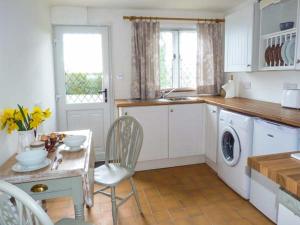 a kitchen with a table and a washing machine at Standard Hill Cottage in Ninfield