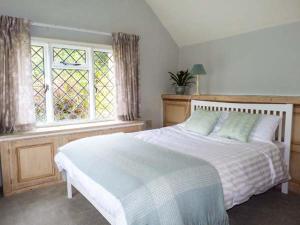 a bedroom with a large white bed with a window at Standard Hill Cottage in Ninfield