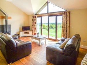 a living room with two leather couches and a large window at Black Mountain View in Llanafan-fawr