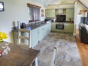 a kitchen with green cabinets and a wooden table at Black Mountain View in Llanafan-fawr