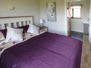 a bed with a purple blanket on it in a bedroom at Black Mountain View in Llanafan-fawr