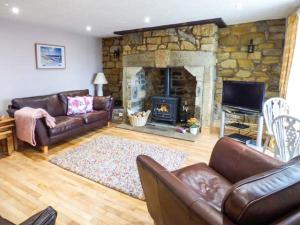 a living room with couches and a stone fireplace at Sandy Knowes in Amble