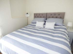 a blue and white striped bed with two pillows at Sandy Knowes in Amble